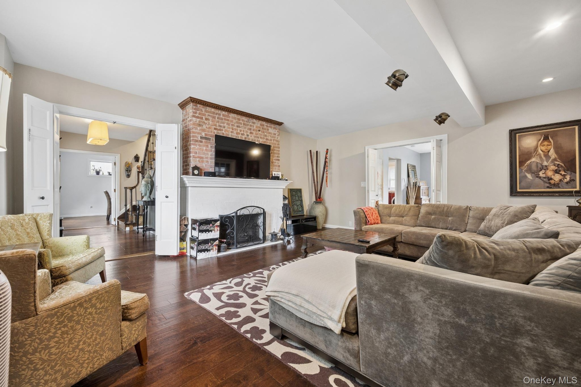 Elegant living room showcasing beautiful hardwood floors, a classic wood-burning fireplace, and a charming bay window that brings in abundant natural 