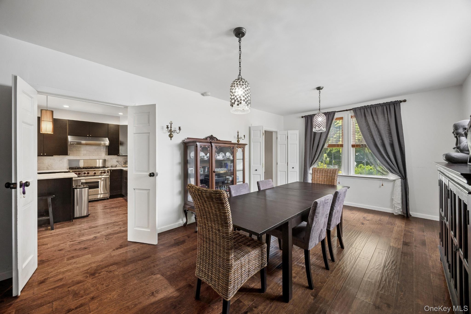 Elegant formal dining room featuring rich hardwood flooring, stylish pendant lighting, and oversized windows that provide abundant natural light. Thou