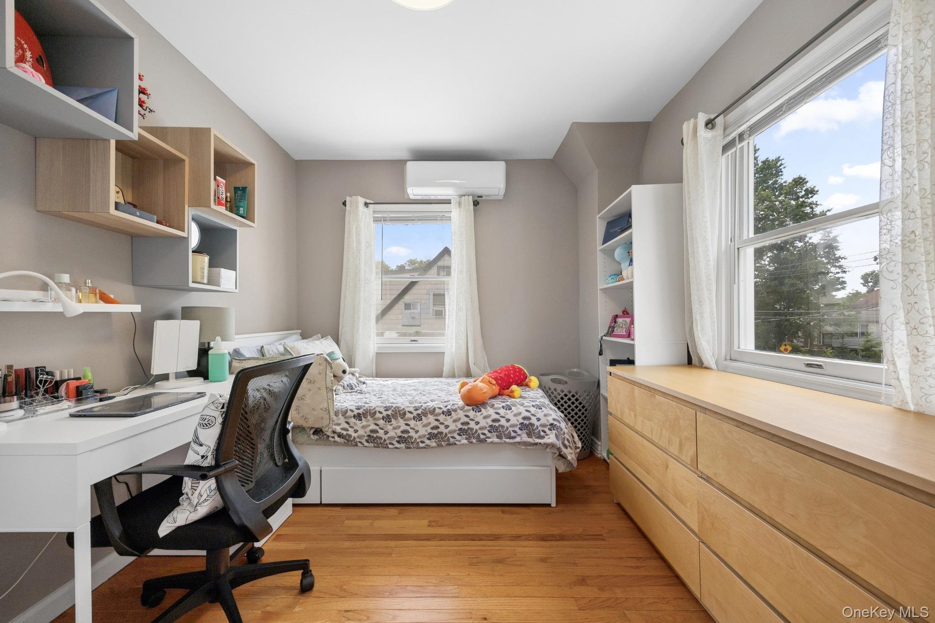Bright and comfortable bedroom featuring beautiful hardwood flooring, large windows that provide abundant natural light, and a functional layout with 