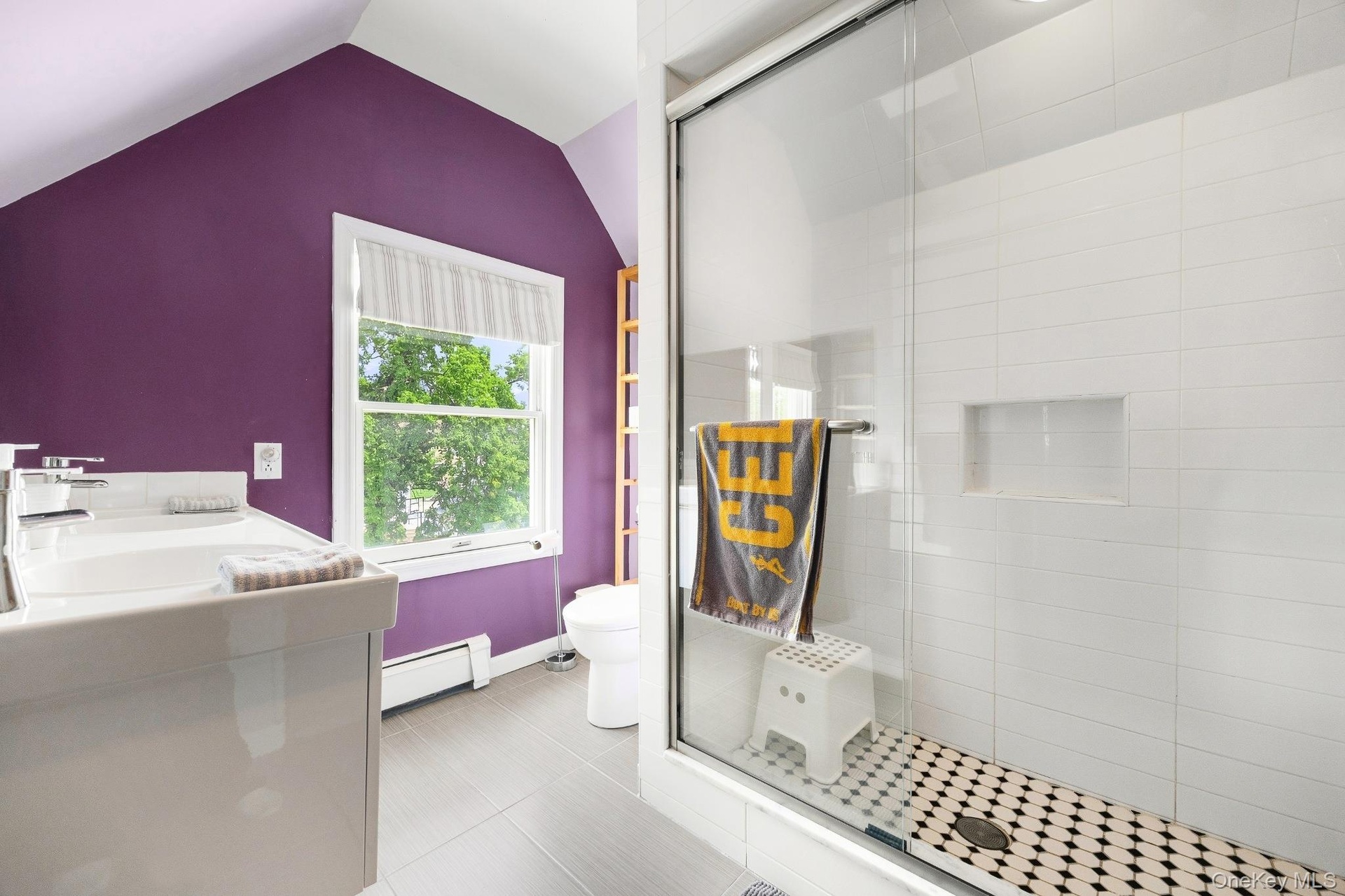 Bright and modern bathroom featuring a spacious glass-enclosed walk-in shower, contemporary tile finishes, and a large window that fills the space wit