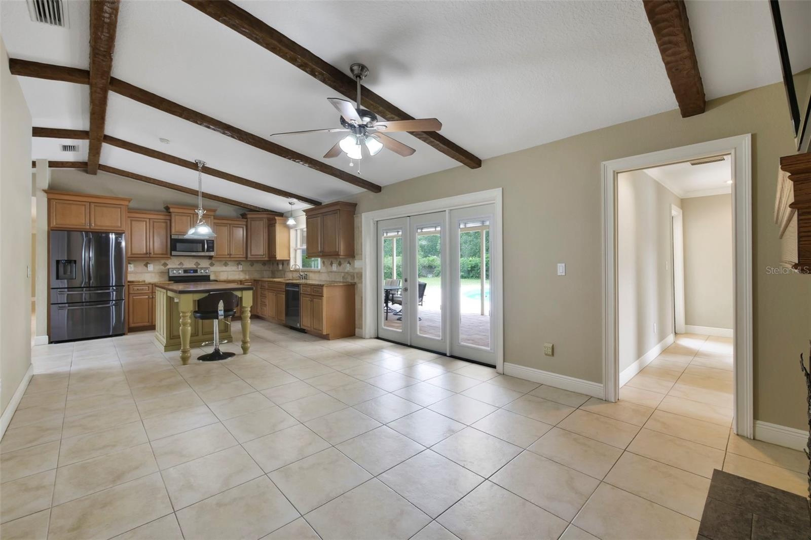 The Living Room is accented by exposed wood ceiling beams, a COZY FIREPLACE, built-in shelving, and NATURAL LIGHT flowing through another set of Frenc