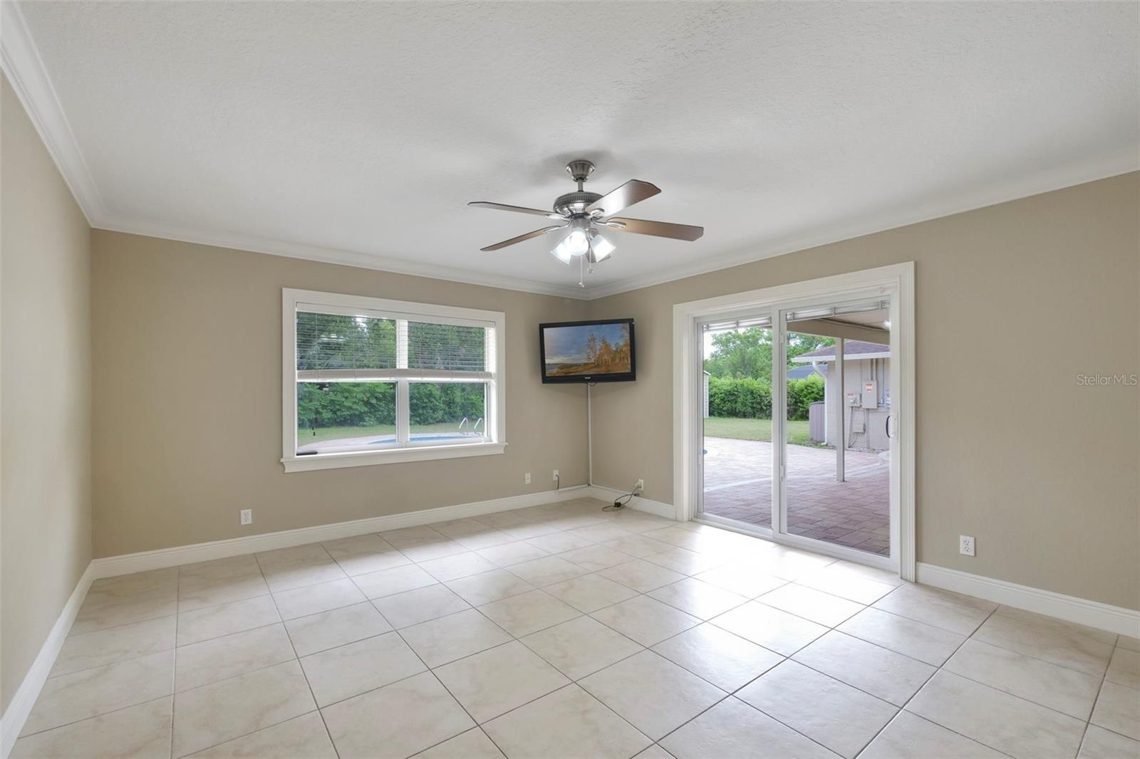 A VERSATILE BONUS SPACE is ideal as a media room, game room, or second living area, with sliding glass doors opening to the patio and pool for seamles