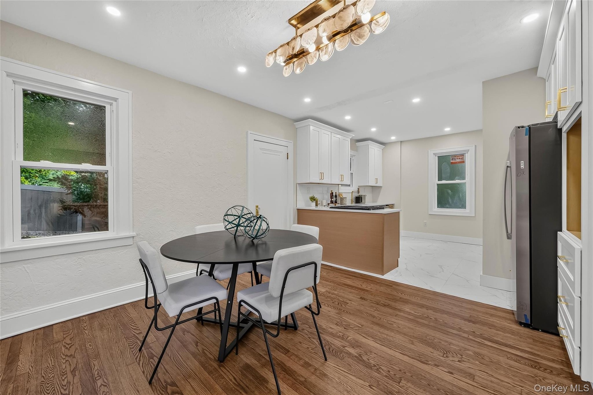 Open-concept dining area featuring wood-finish flooring, a contemporary chandelier, and recessed lighting