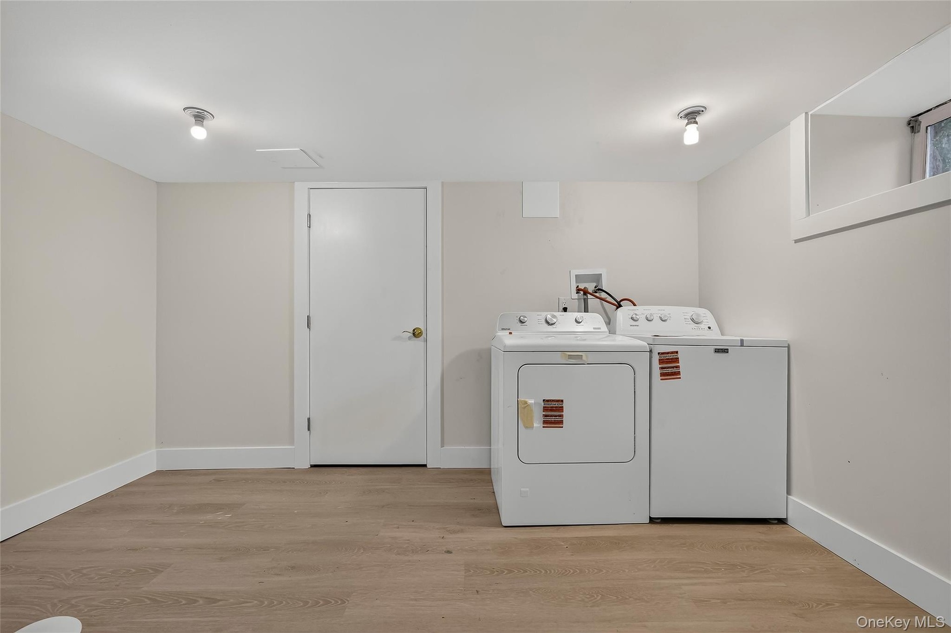 Dedicated laundry area featuring a washer and dryer, wood-finish flooring, and a window for natural light