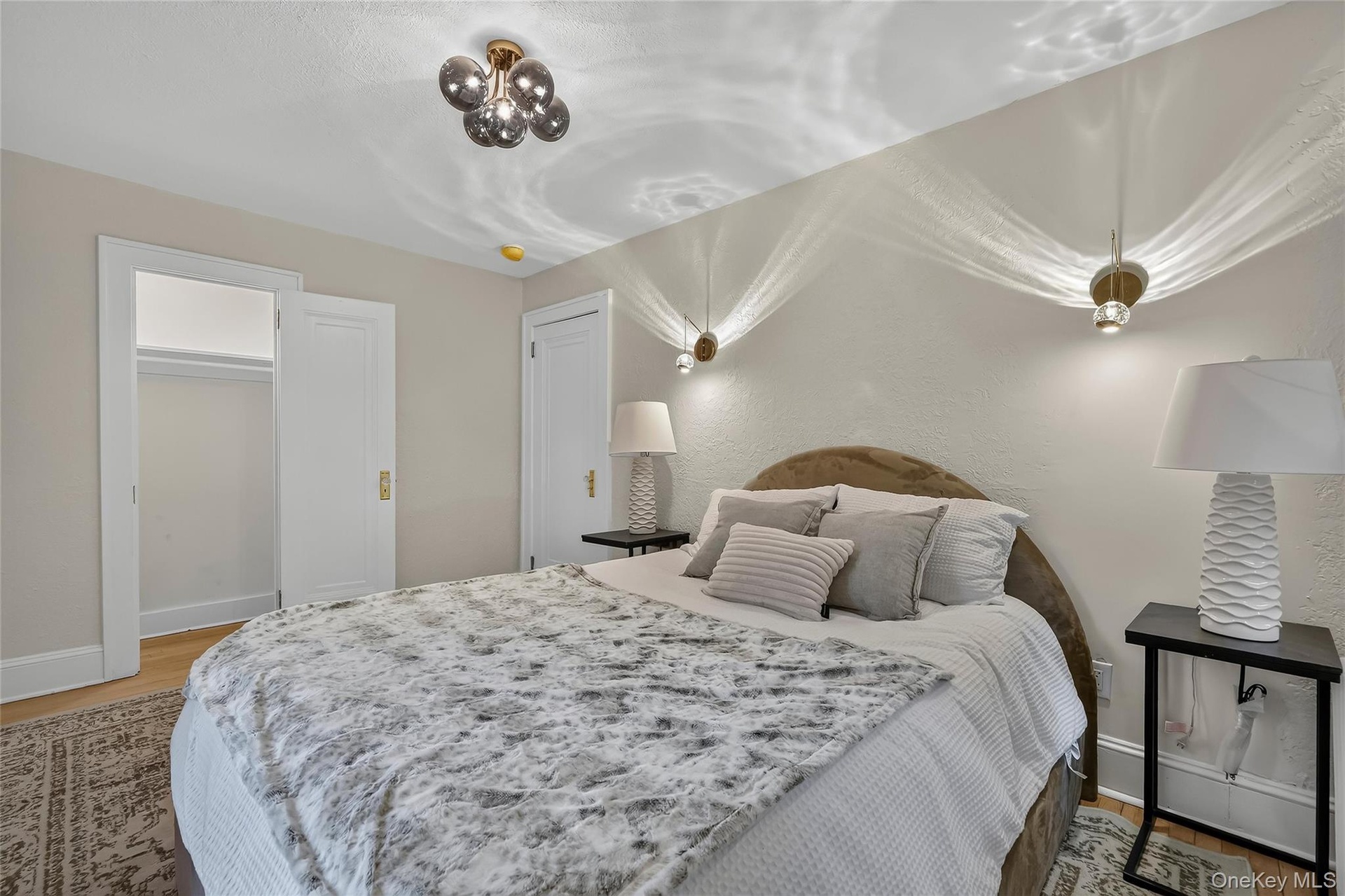 Bedroom with ceiling-mounted lighting fixture and two wall-mounted sconces