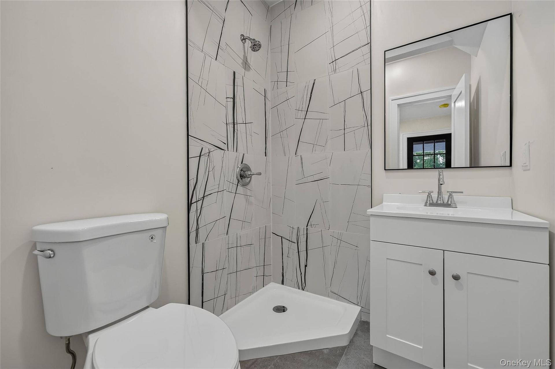 Modern bathroom featuring a corner shower with abstract tilework, a white shower pan, and chrome fixtures