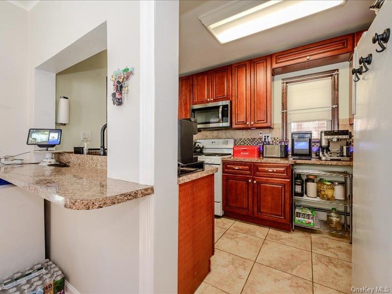 Kitchen featuring cherry wood-finish cabinetry, tile flooring, and a pass-through window