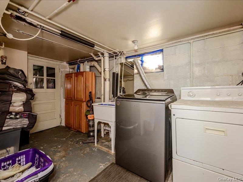 Laundry area featuring a utility sink, exposed piping, and a glass-paneled door