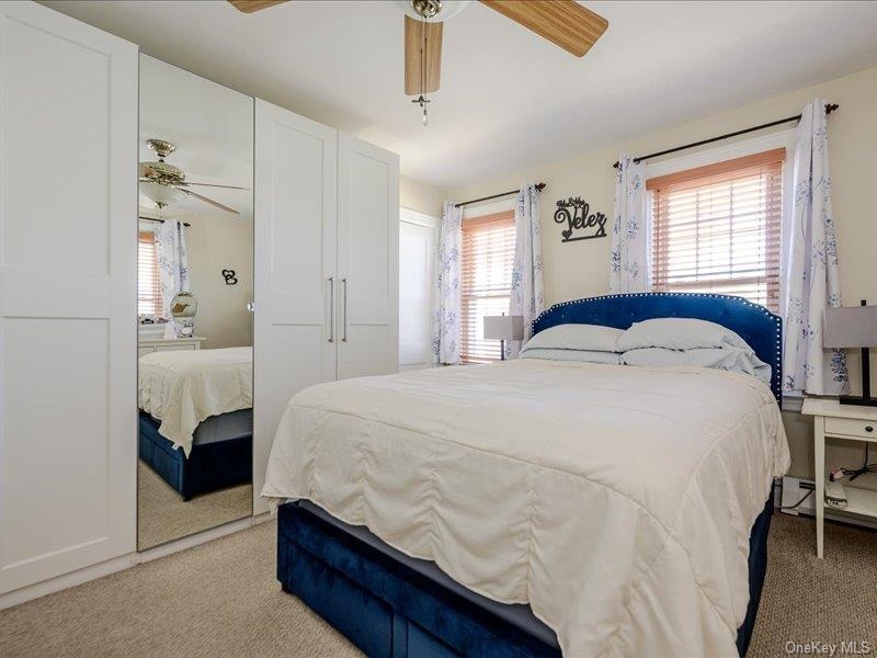 Master Bedroom featuring light beige carpeting, two windows with wood blinds, and a ceiling fan with wood-finish blades