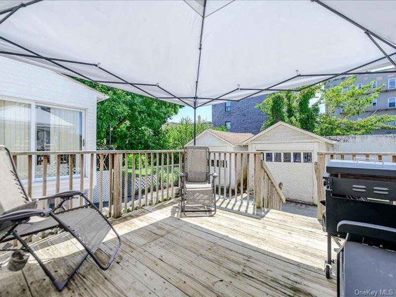 Expansive wood-finish deck with a wood railing and a white tent for shade