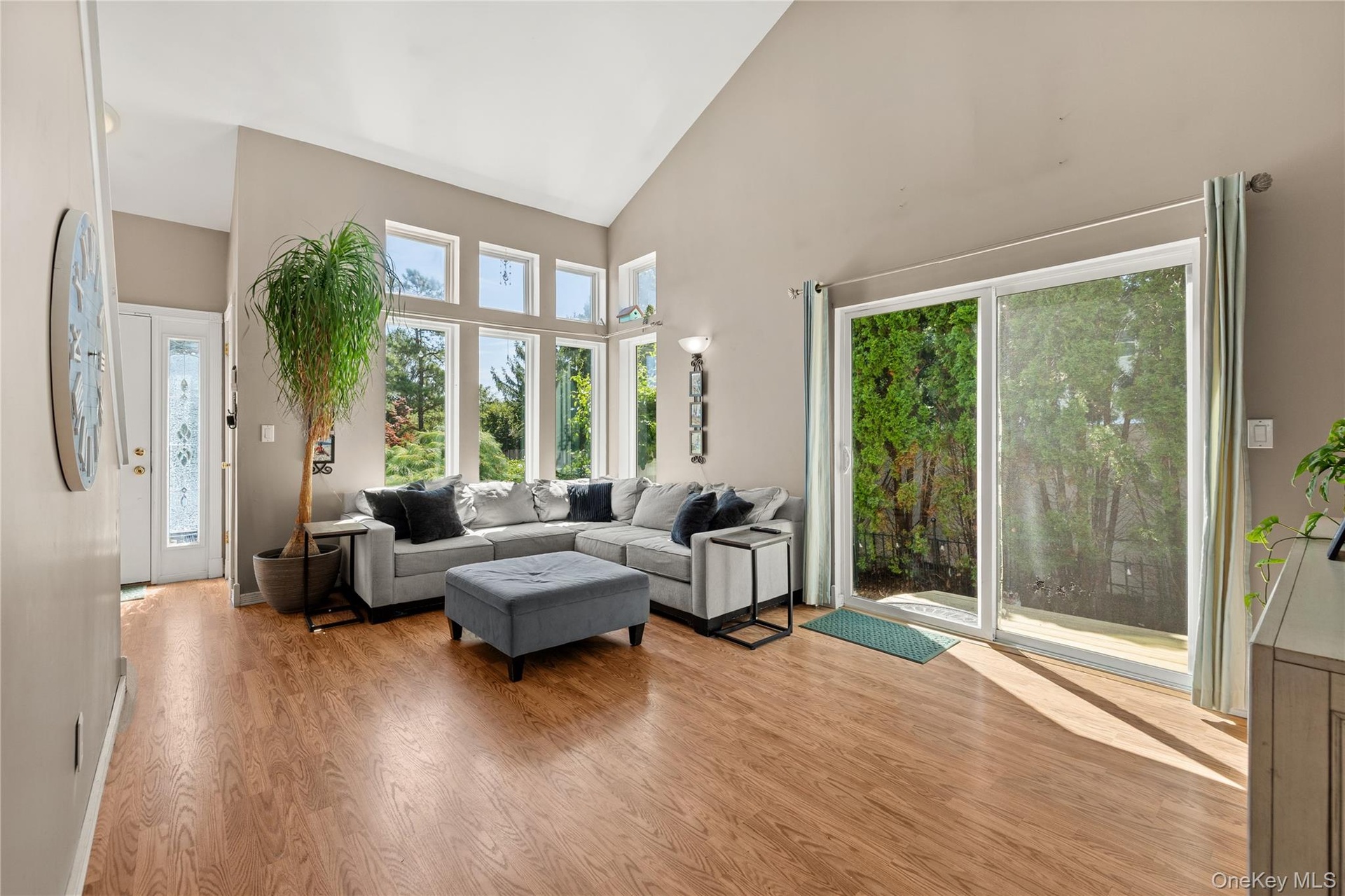 Vaulted ceiling with a wall of windows, wood-finish flooring, and a sliding glass door