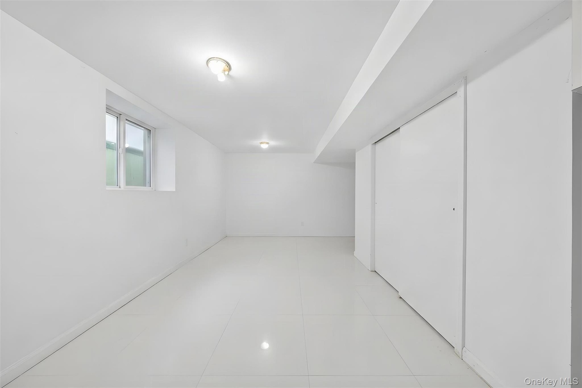 Bright, open room featuring polished light-toned flooring, pristine white walls, and recessed ceiling lighting