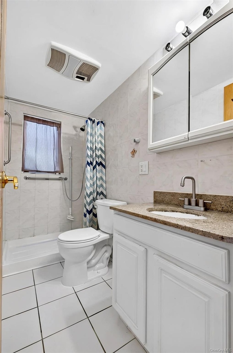 White vanity with a stone-finish countertop and undermount sink