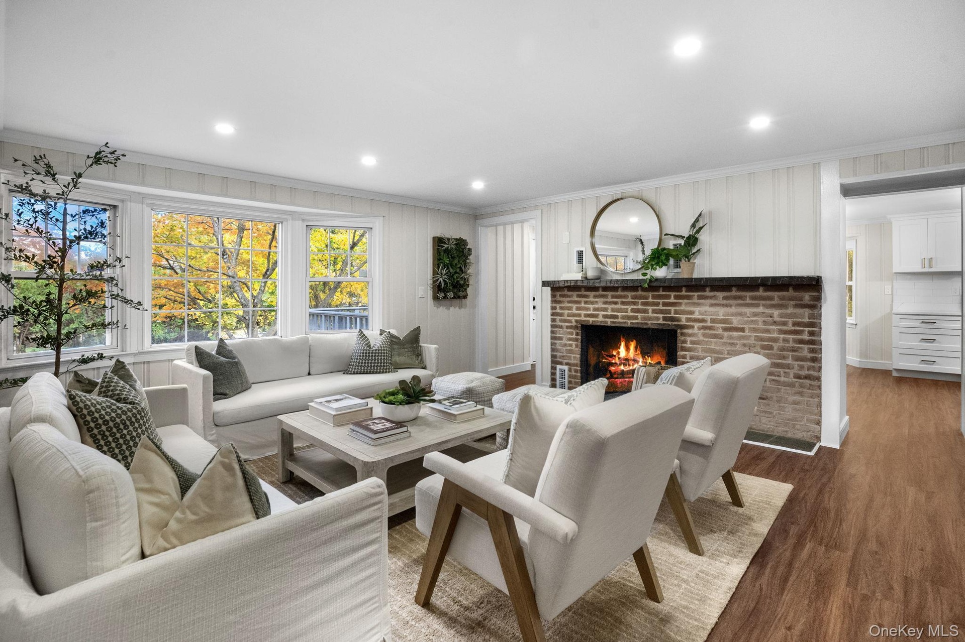 A beautifully reimagined living space filled with natural light, where wide picture windows and a glowing fireplace create the perfect spot to unwind.
