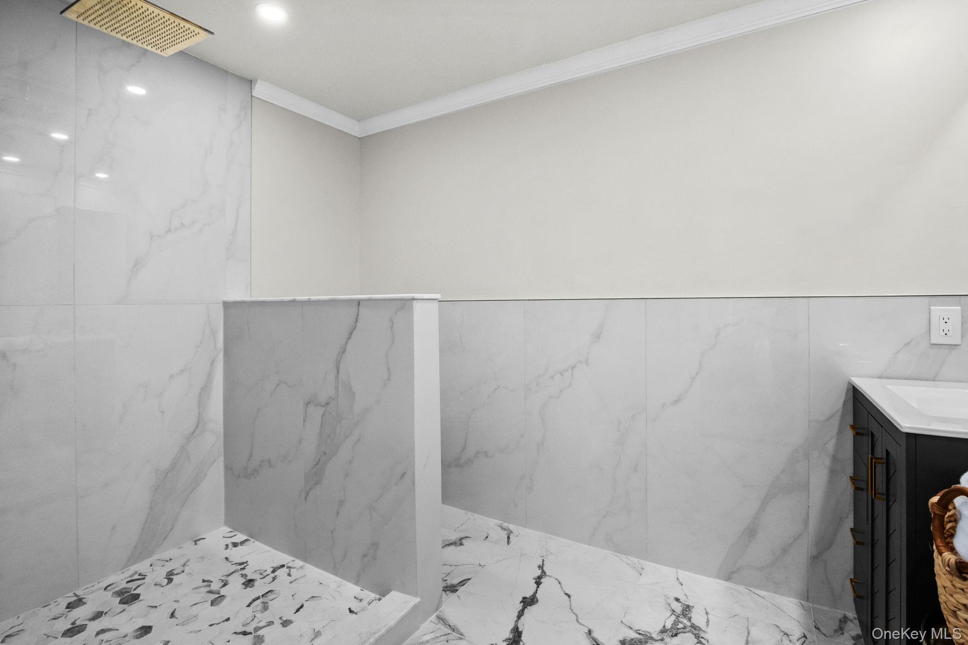Walk-in shower with marble-style tile, frameless half wall, and rainfall showerhead for a spa-inspired experience.