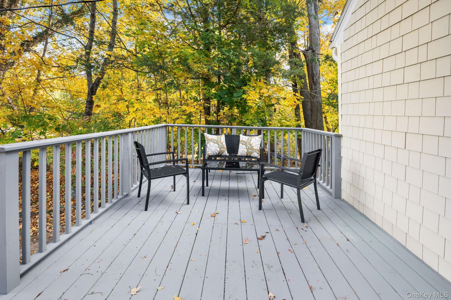 Freshly painted front porch surrounded by mature trees, offering a peaceful spot to enjoy morning coffee or unwind outdoors.