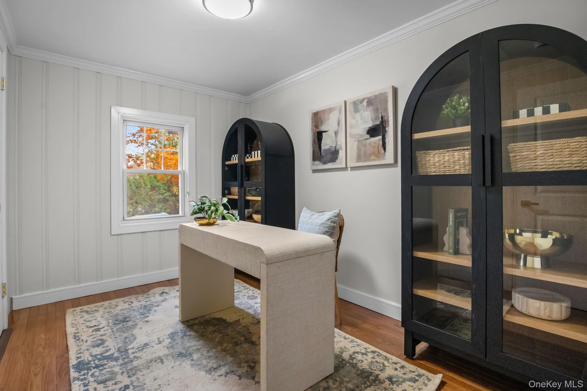Flexible home office with hardwood floors, crown molding, and natural light creating an ideal workspace or study area.