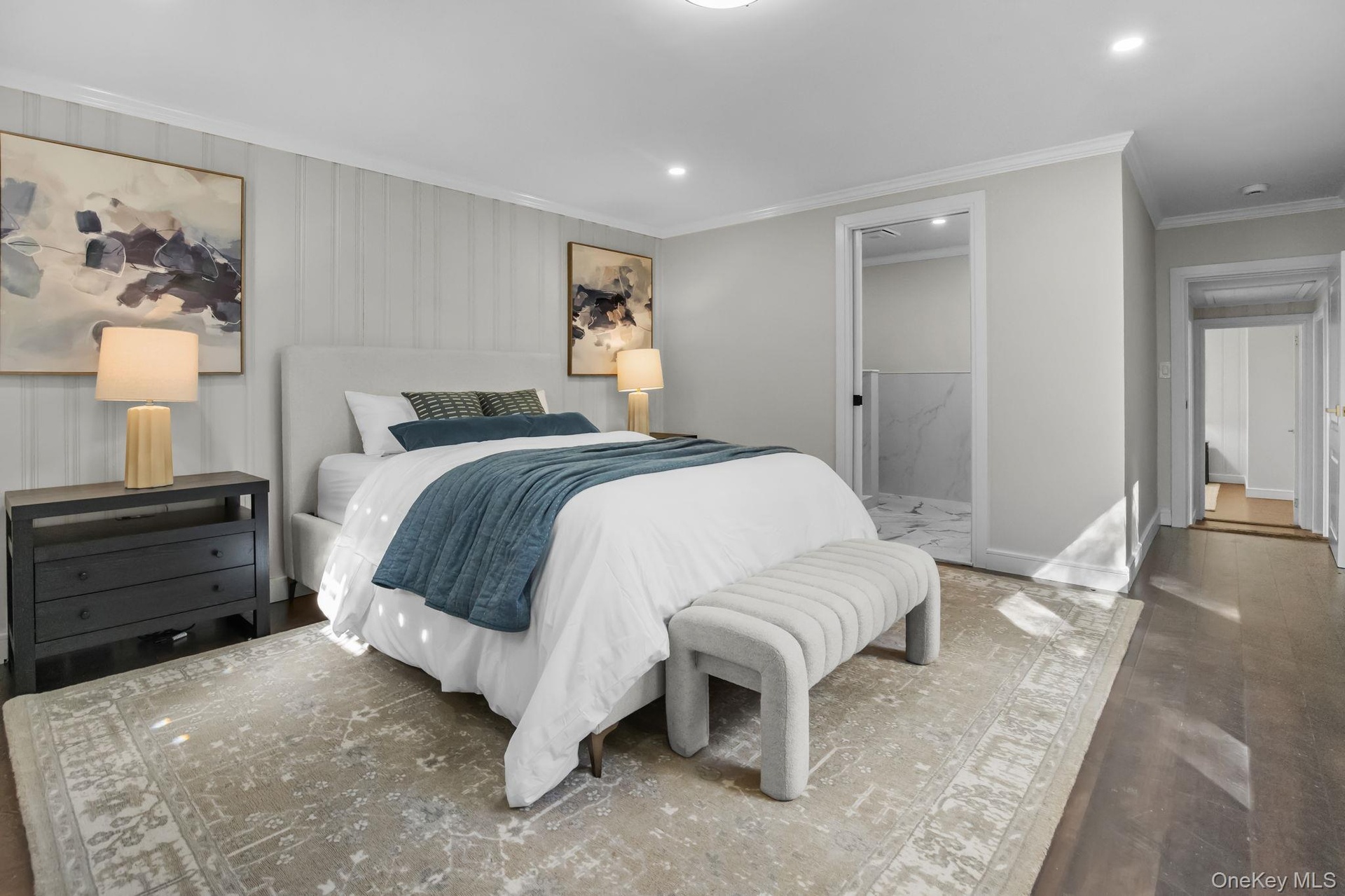 Bright and spacious primary bedroom with hardwood floors, crown molding, and direct access to the ensuite bath.
