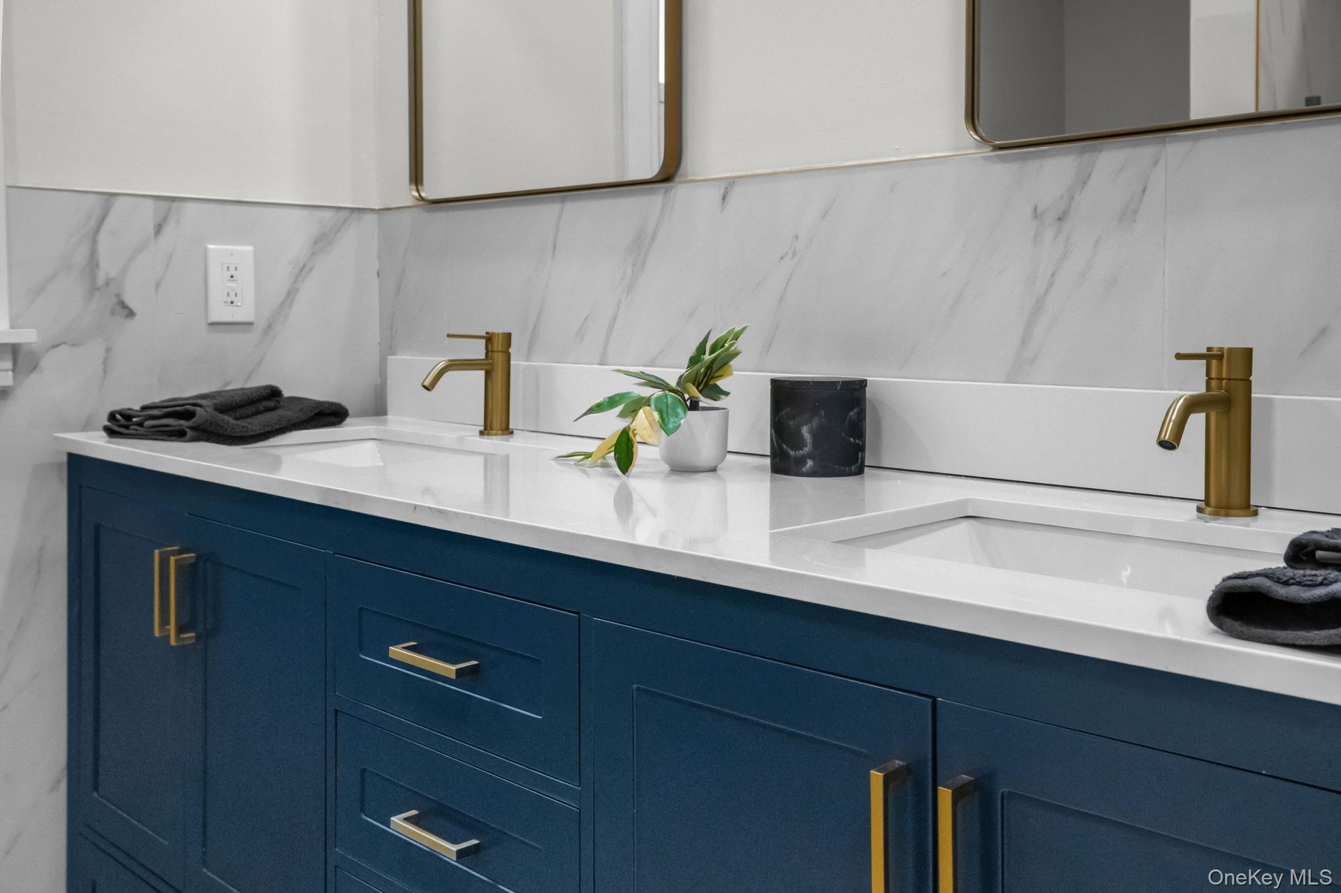 Rich navy cabinetry paired with quartz counters and gold hardware creates a sophisticated yet serene space perfect for daily routines or a spa-like un