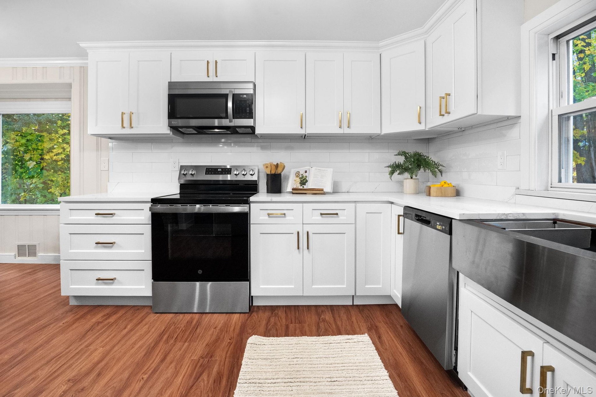 Newly renovated kitchen featuring stainless steel appliances, quartz countertops, and elegant white shaker cabinetry accented with brushed gold hardwa