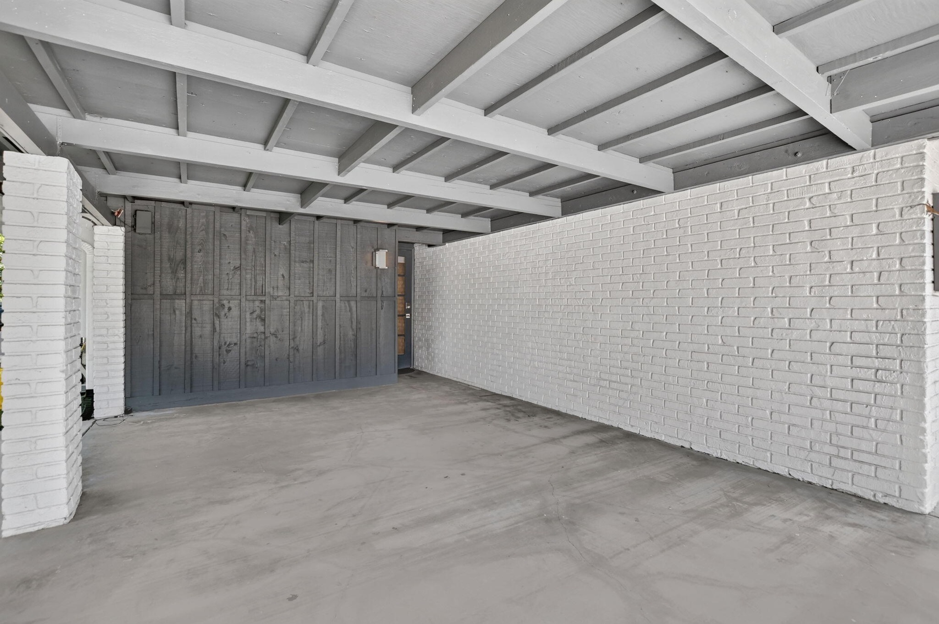 This oversized carport has plenty of room for a typical SUV with room to walk around the vehicle. It has lighting and an entrance door to the house. P