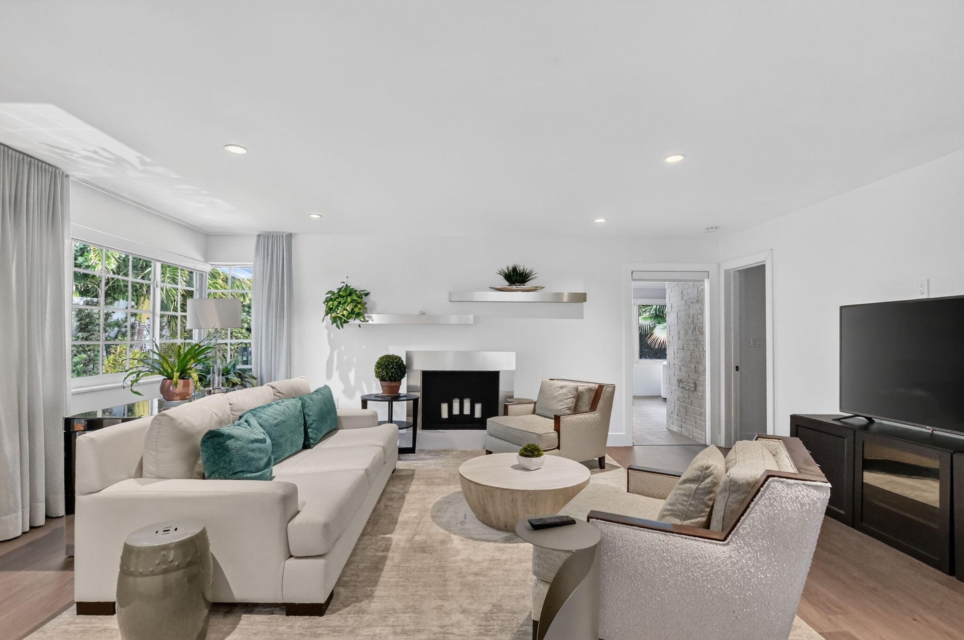 This spacious and bright family room (view from kitchen) has lots of widows ceiling lights on a dimmer, large wall for a Big screen TV with access to 