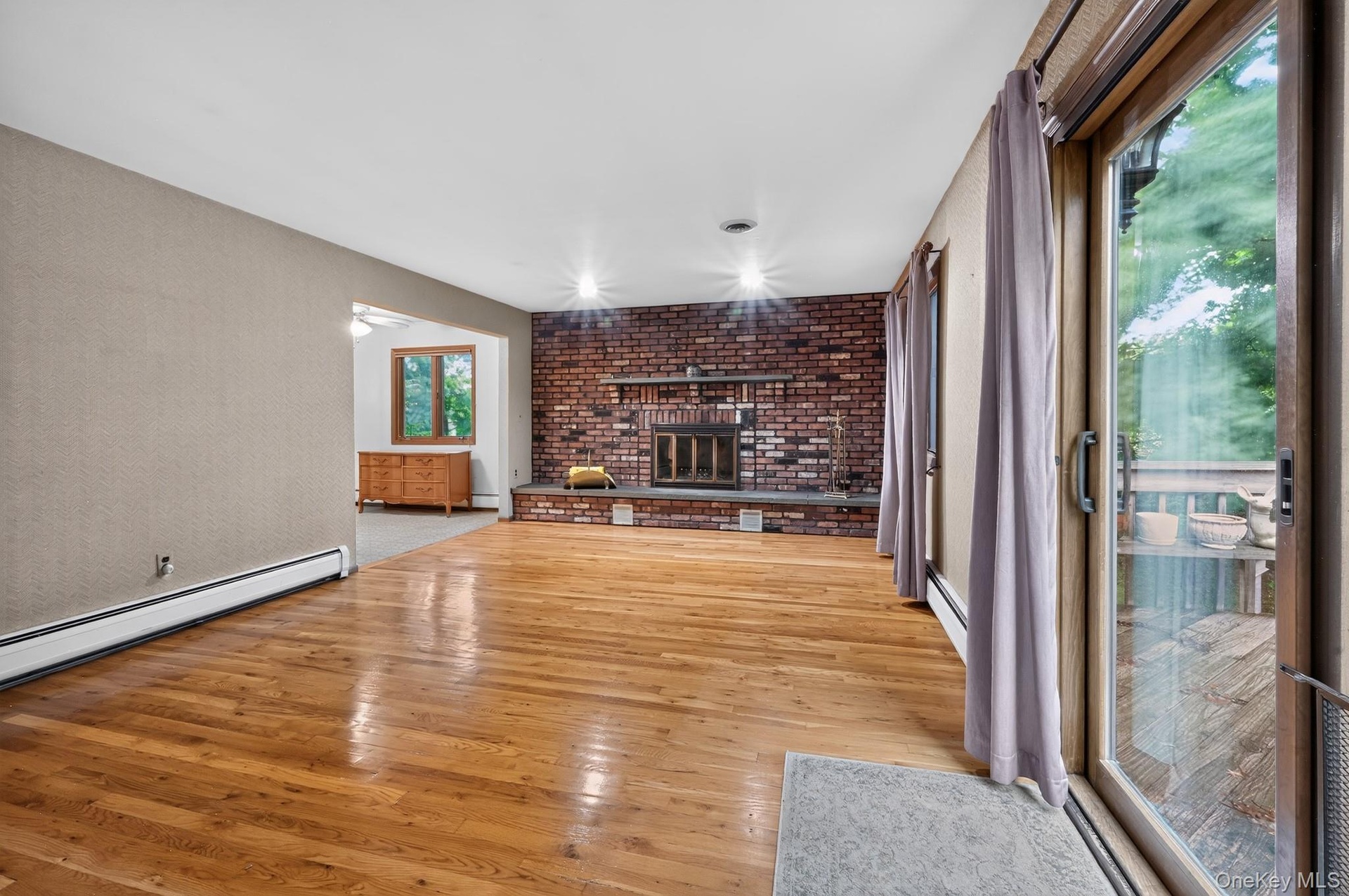 A warm and inviting family room featuring a classic full-wall brick fireplace equipped with built-in ventilator fans, with sliding glass doors leading