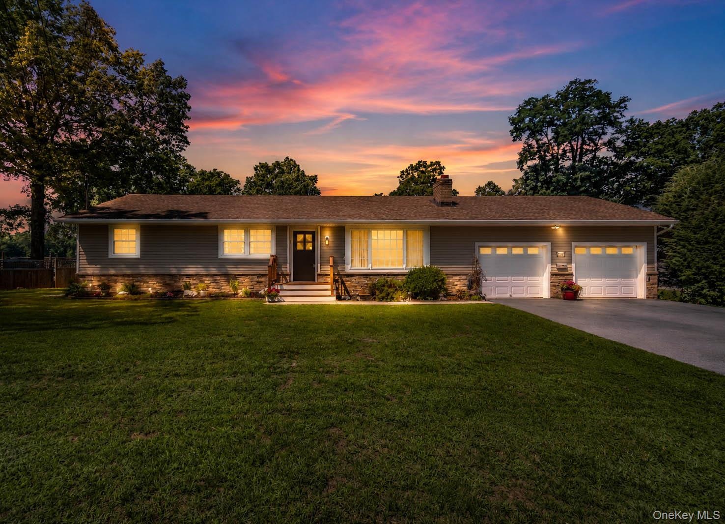 Siding exterior with stone veneer accents, multi-pane windows, covered entry, and attached two-car garage