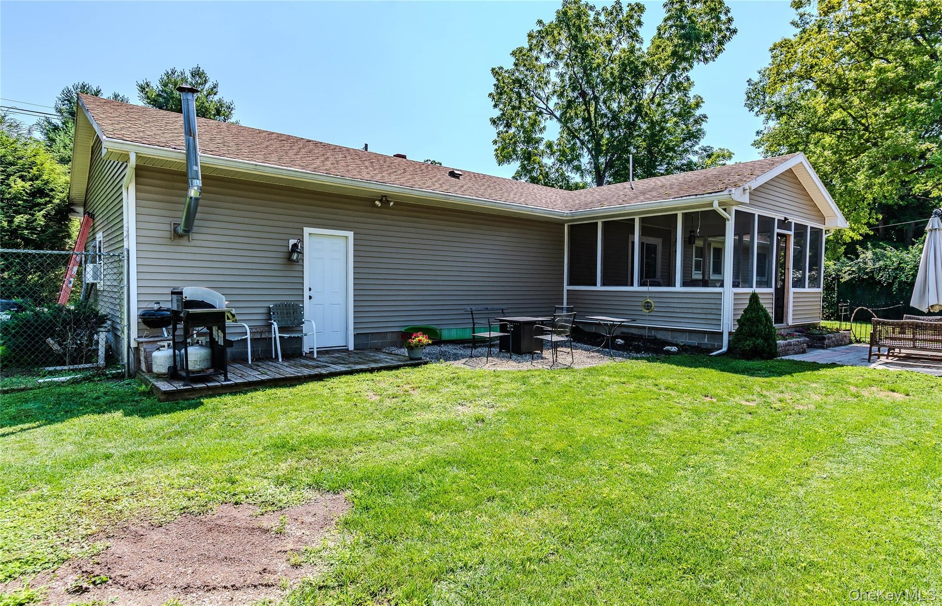 Backyard featuring a screened porch, paver patio, sitting area with fire pit and neutral-toned siding