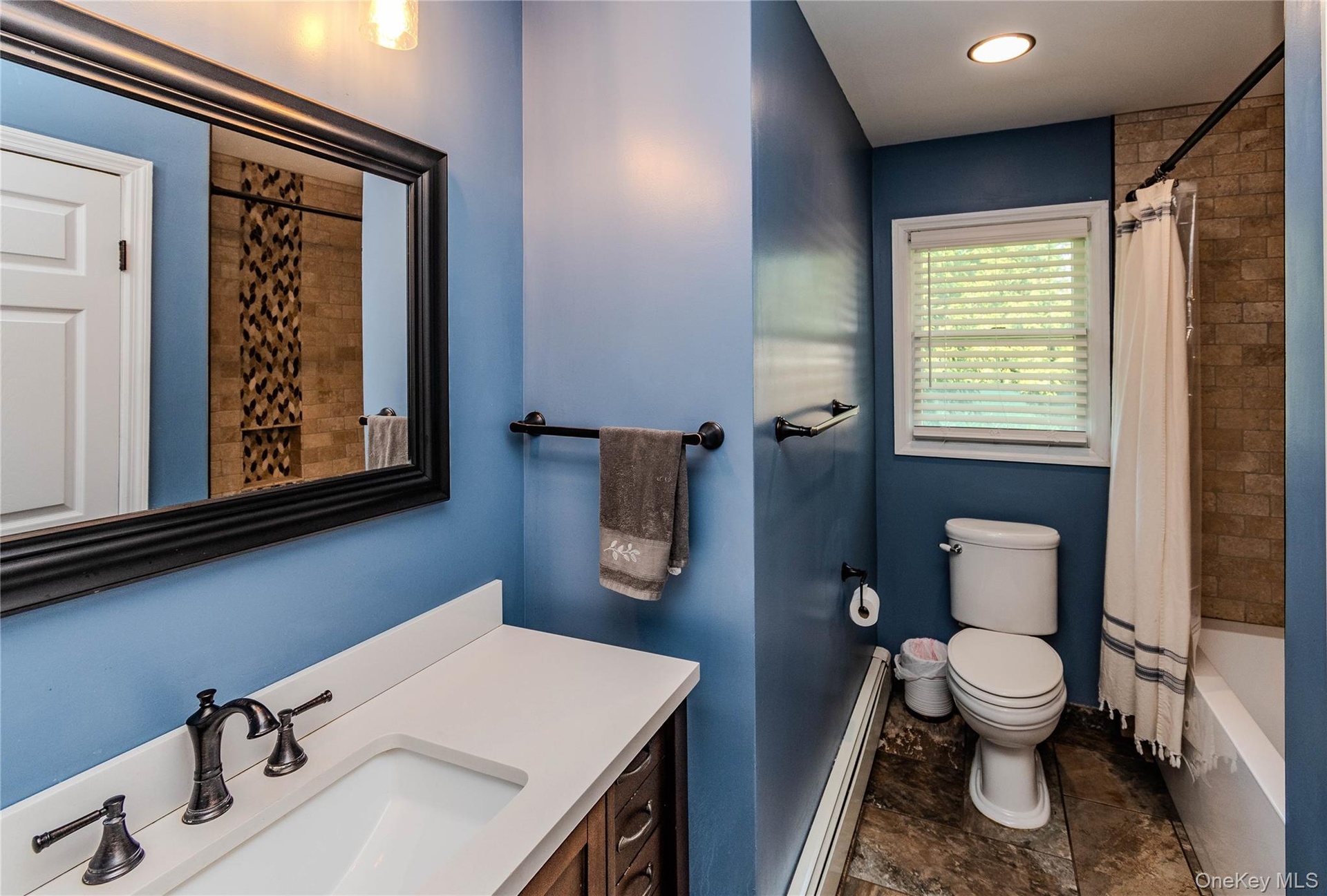 Hall Bathroom featuring a white vanity with a rectangular sink, bronze-finish faucet, and a large framed mirror