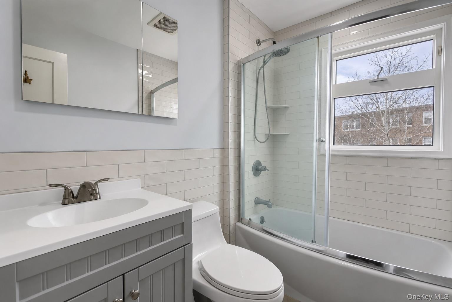 Bathroom featuring a single vanity with a gray cabinet, white countertop, and integrated sink