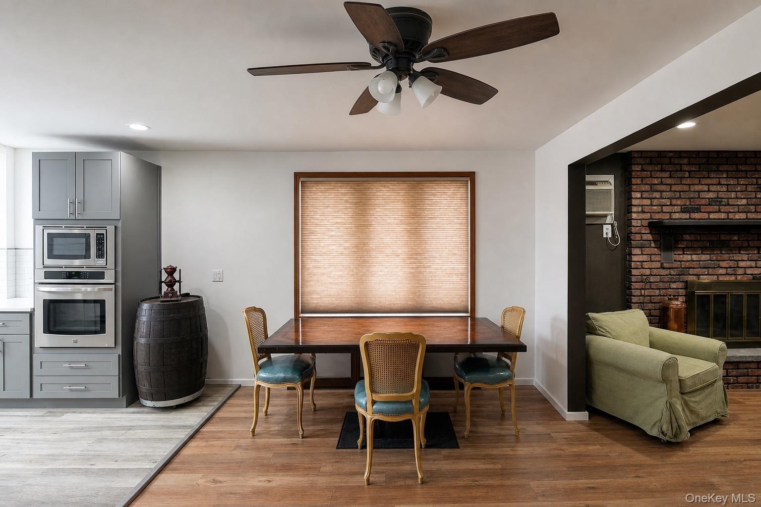 Wood-finish flooring, recessed lighting, ceiling fan light fixture, built-in stainless steel appliances, and brick fireplace