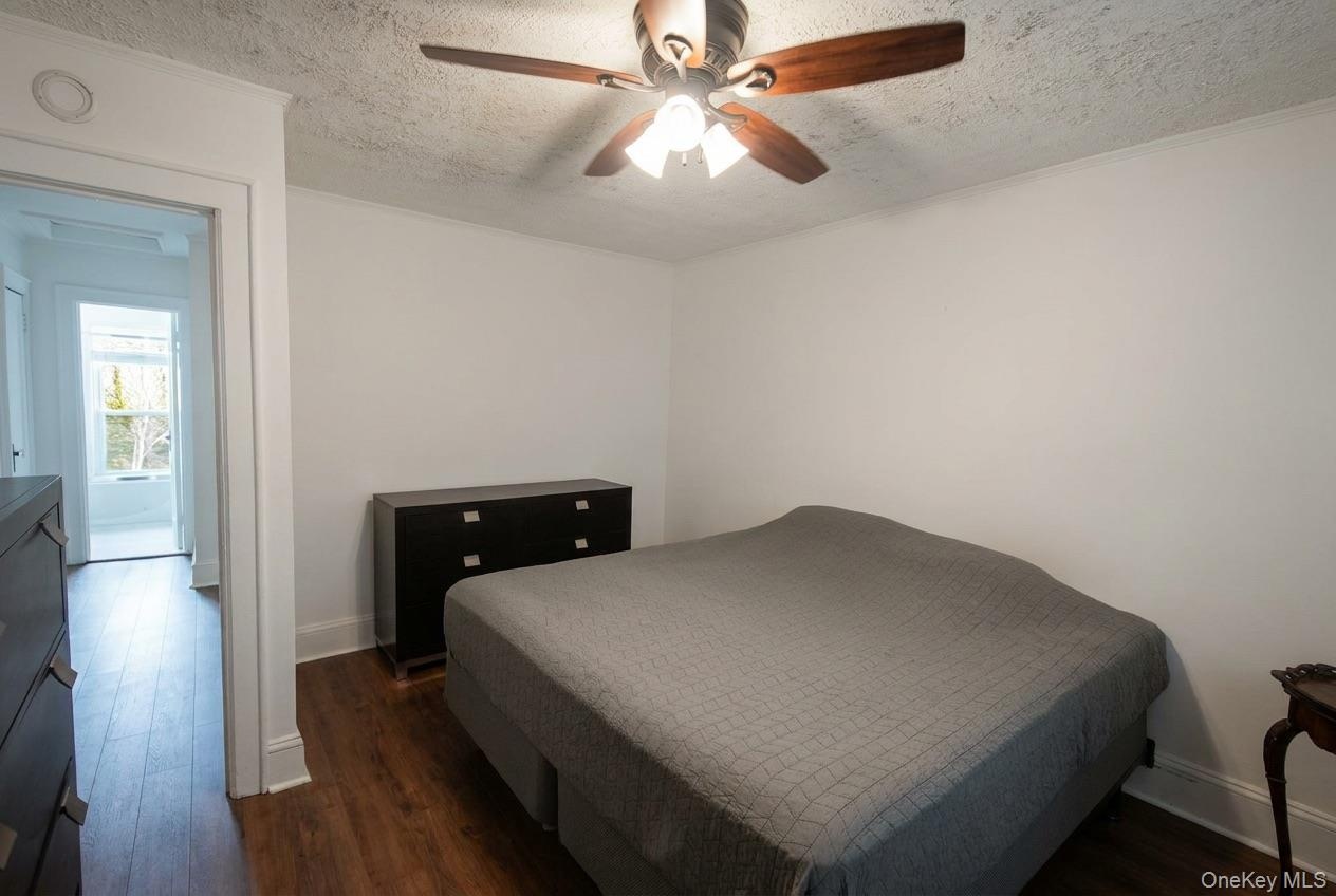 Wood-finish flooring, white walls, and a ceiling fan with integrated lighting