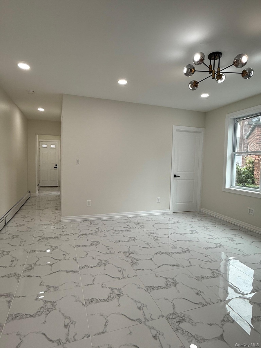 Spacious room featuring large format tile flooring, recessed lighting, and a modern chandelier