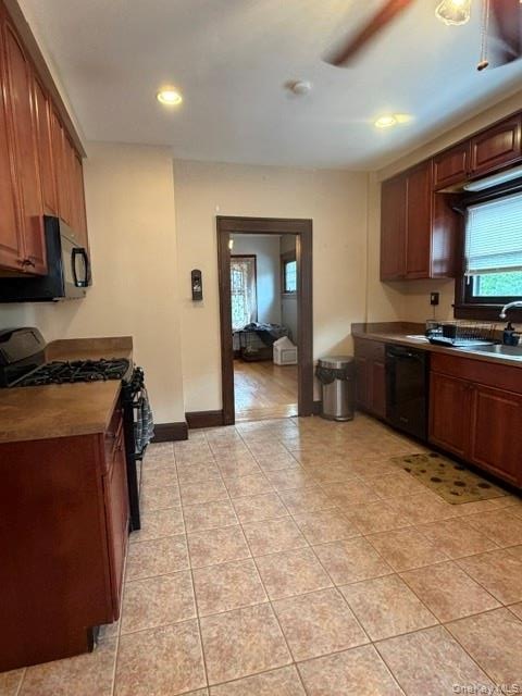 Kitchen featuring wood cabinetry, integrated black appliances, and a tile floor