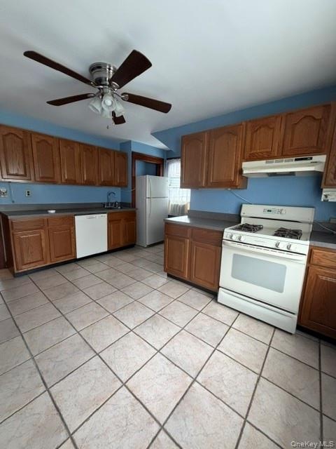Kitchen featuring wood-finish cabinetry, white appliances, and a tiled floor. Apt. 2