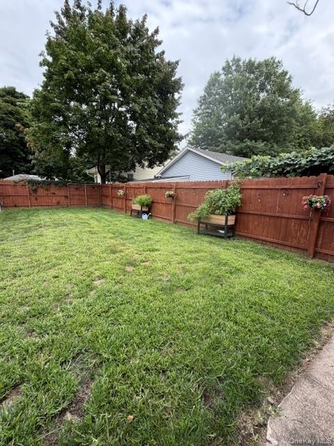 Expansive backyard featuring a wood privacy fence, mature trees, and a concrete perimeter