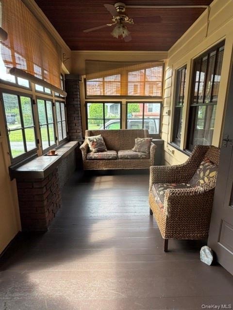 Enclosed porch featuring dark wood-finish flooring, a wood-paneled ceiling, and multiple windows with natural light