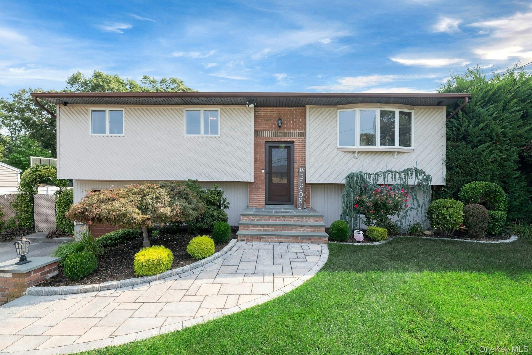 Split-level residence featuring a brick facade, bay window, and a paver pathway