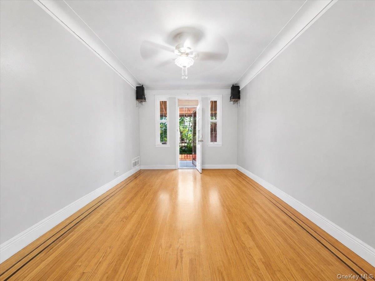 Hardwood flooring with decorative inlay, ceiling fan with light fixture, and crown molding
