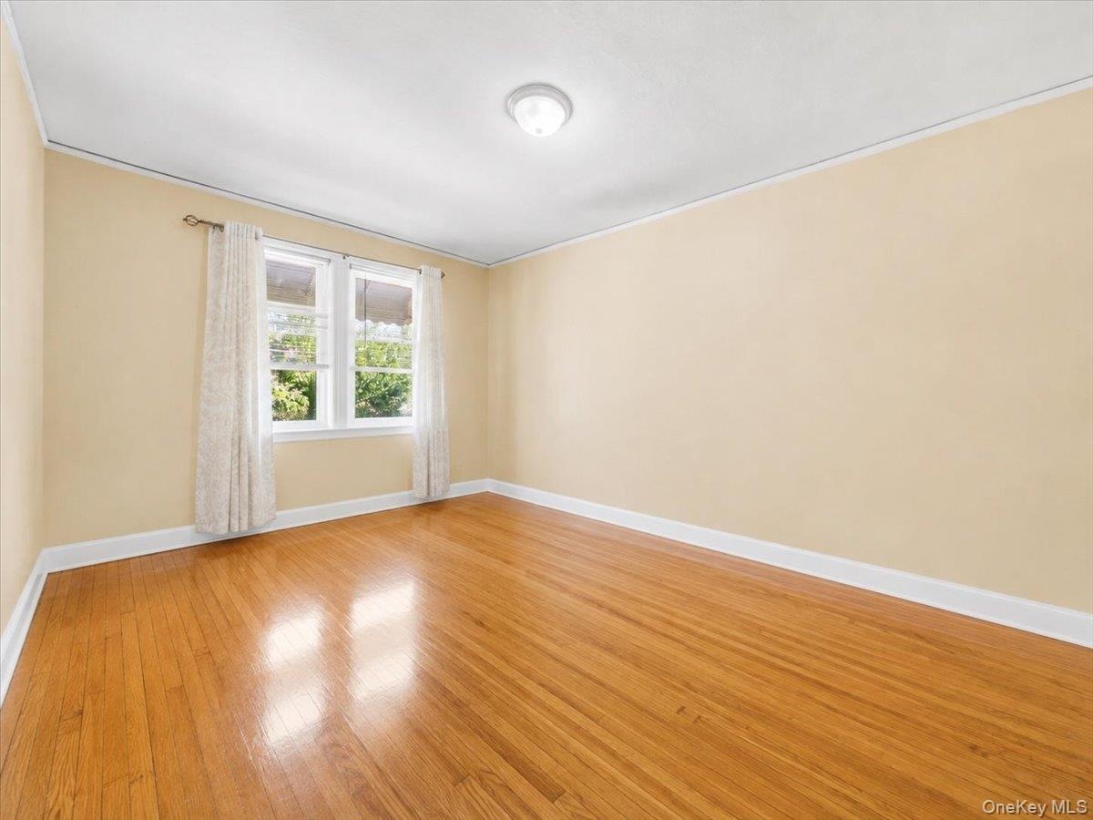 Hardwood flooring, dual windows, white trim, light-colored walls, and a ceiling-mounted light fixture