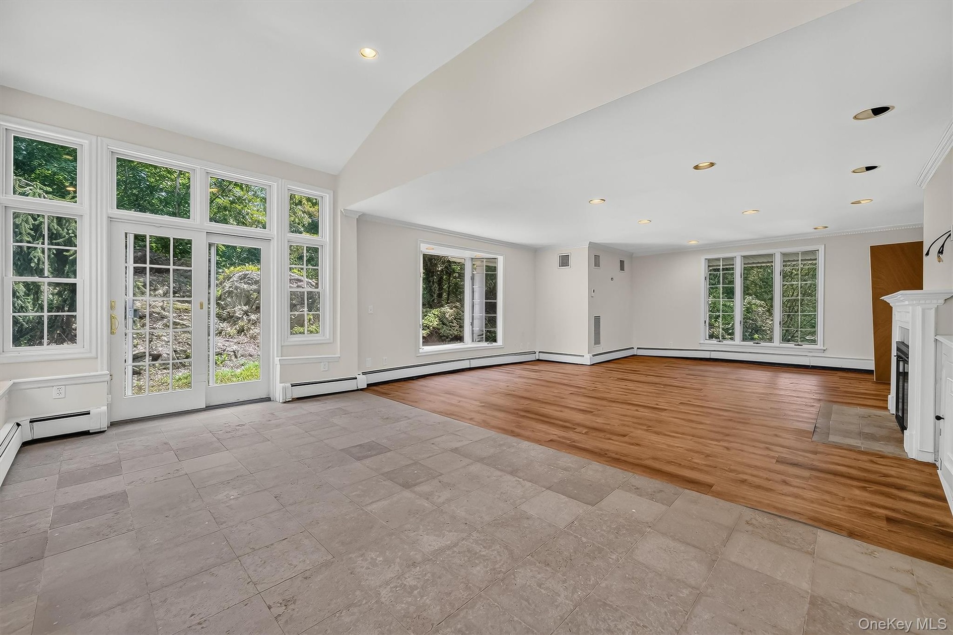 Expansive room featuring wood-finish flooring, a white mantel fireplace, and recessed lighting