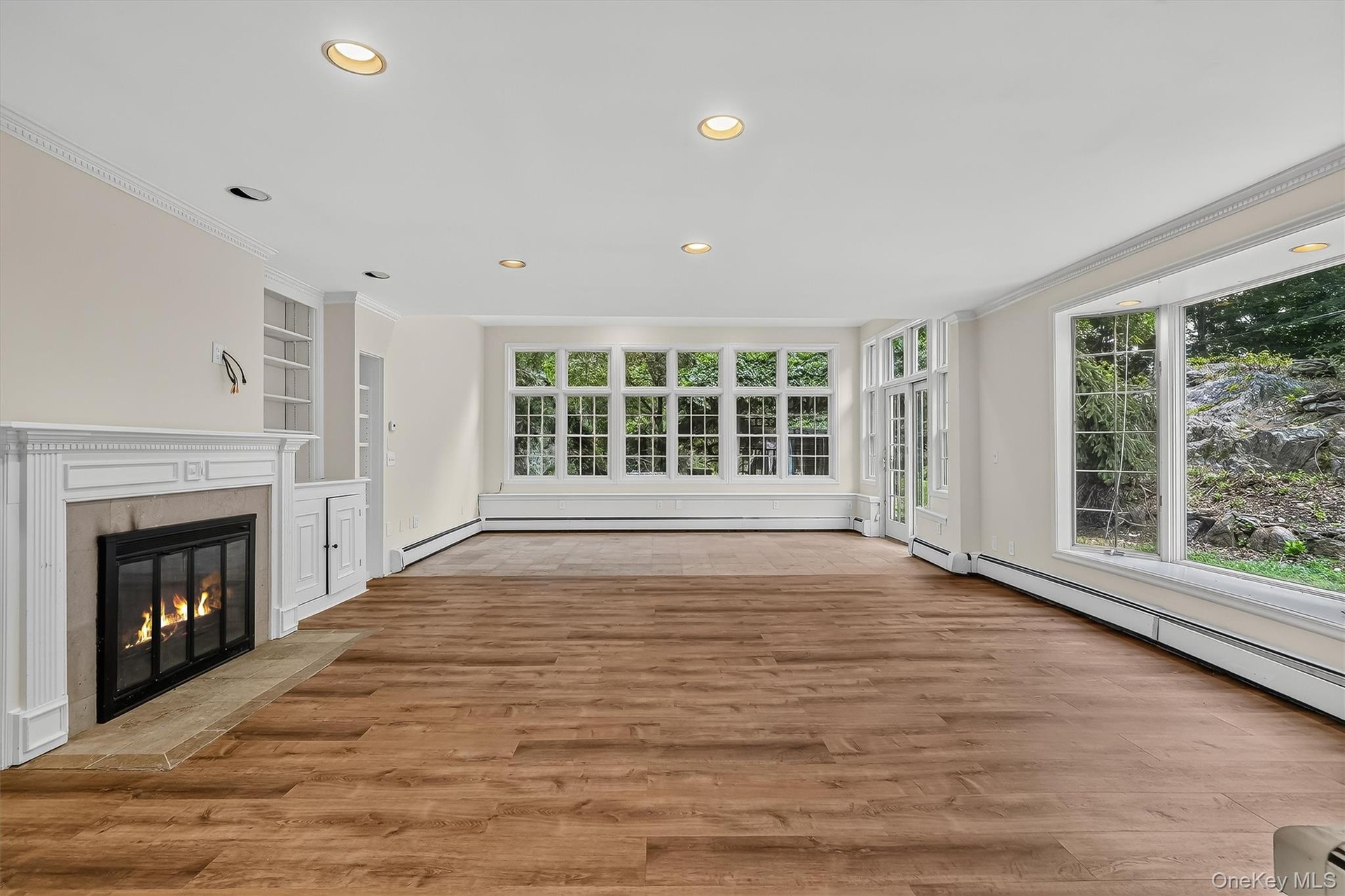 Wood-finish flooring, recessed lighting, and a white mantel fireplace with a stone hearth