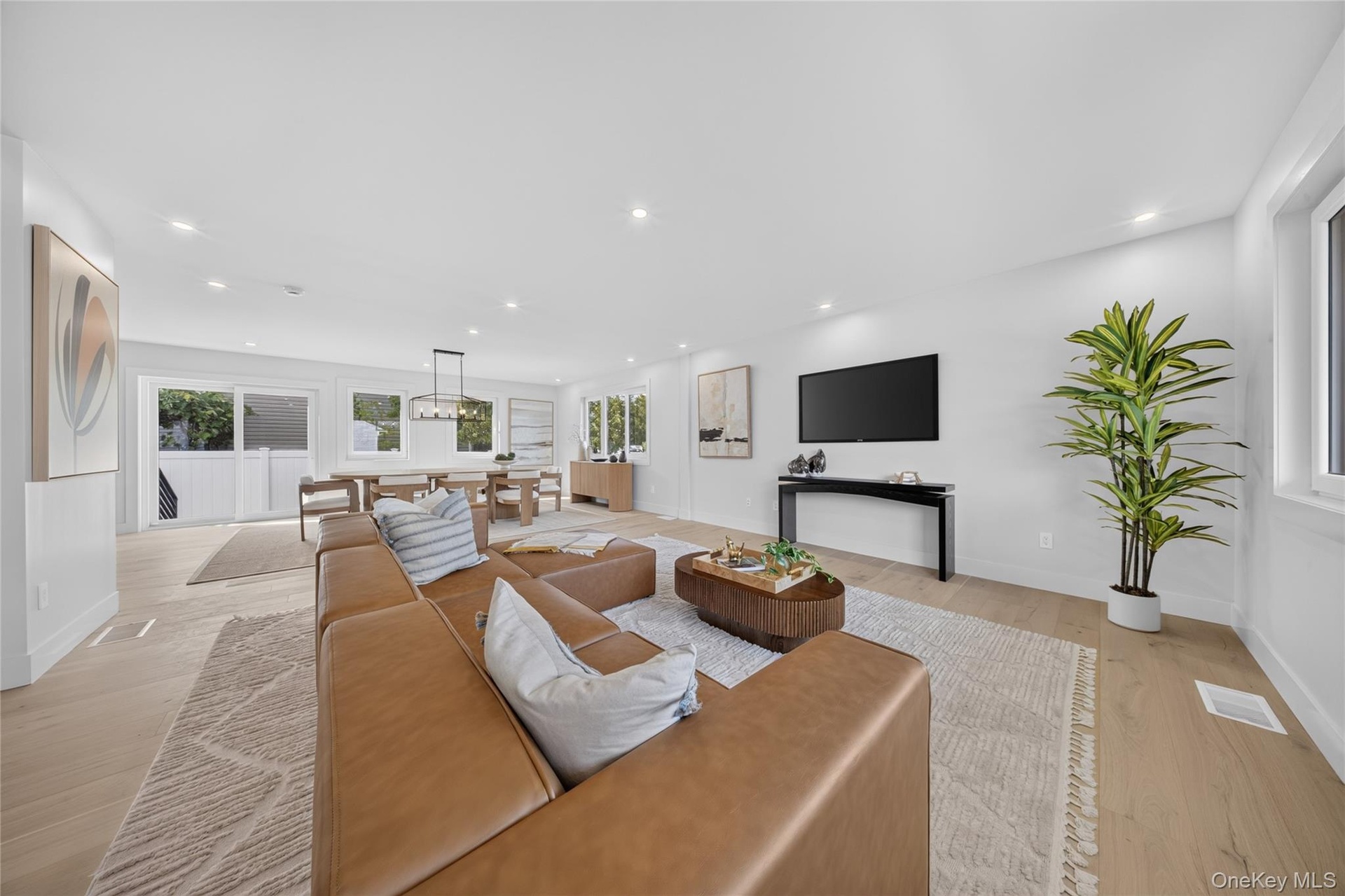 Open-concept living area featuring wood-finish flooring, recessed lighting, and expansive windows