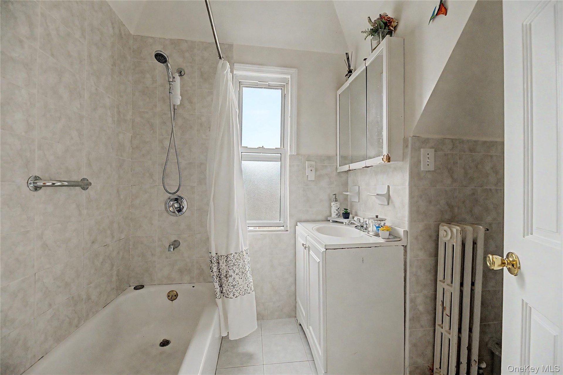 Bright, tiled full bathroom with tub and shower.