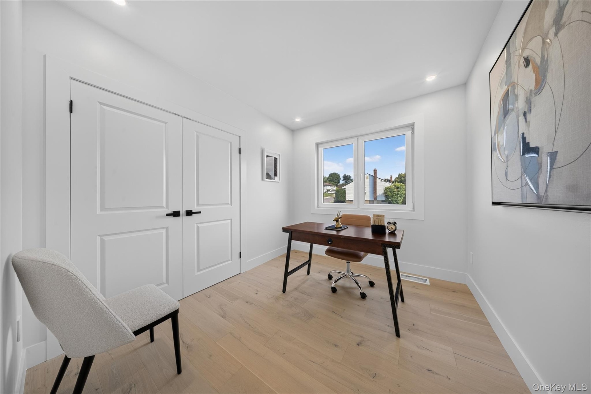Recessed lighting, wood-finish flooring, and white walls with thick baseboards