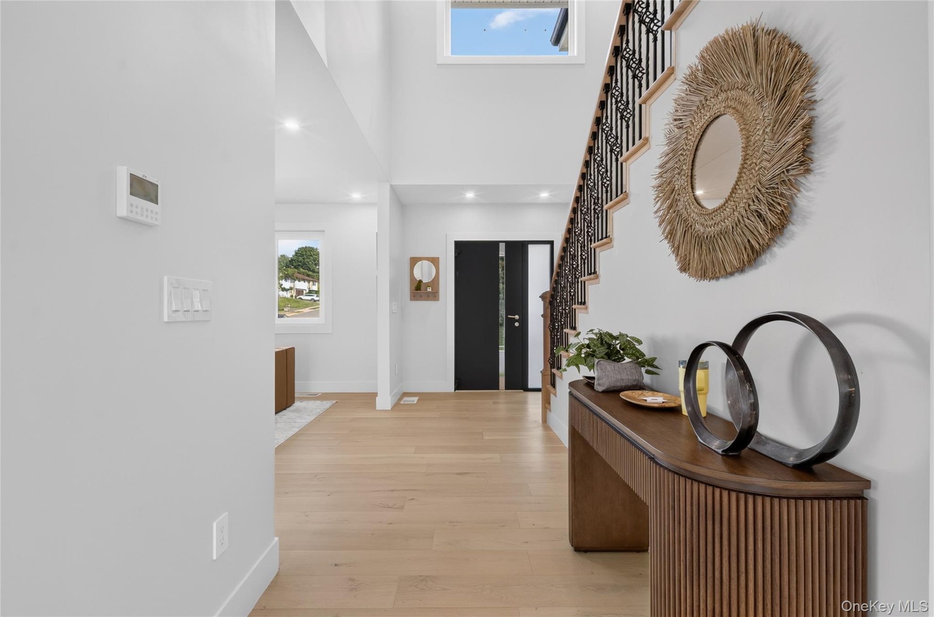 Double-height entryway with recessed lighting, wood-finish flooring, and a staircase featuring a wrought iron railing
