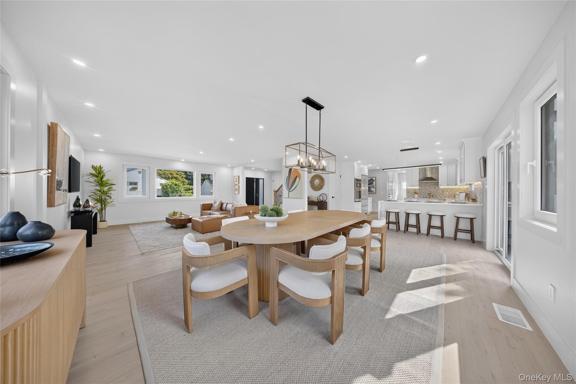 Open-concept living space featuring light wood-finish flooring, recessed lighting, and white walls