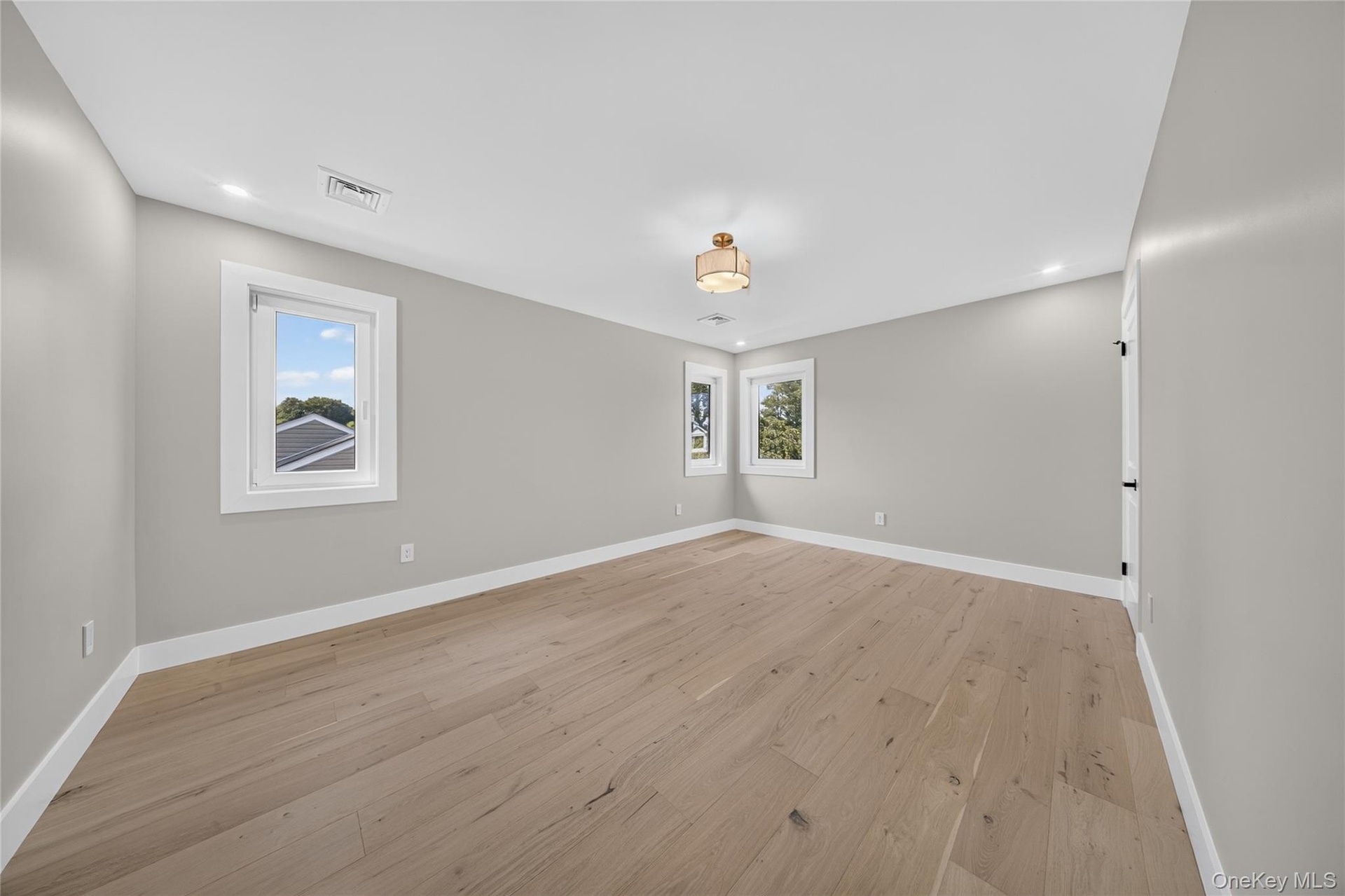 Light-toned wood-finish flooring, recessed lighting, central ceiling fixture, and multiple windows