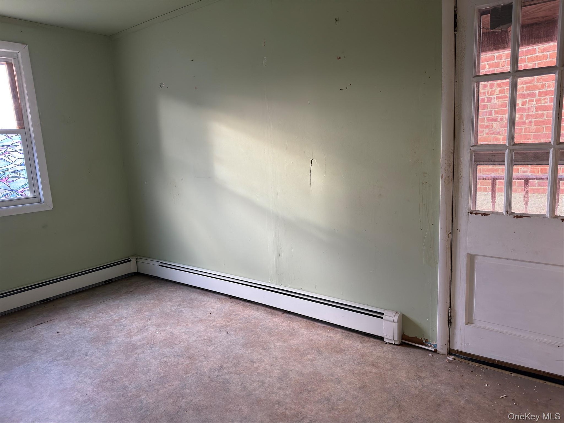 Spare room featuring plenty of natural light, baseboard heating, and carpet